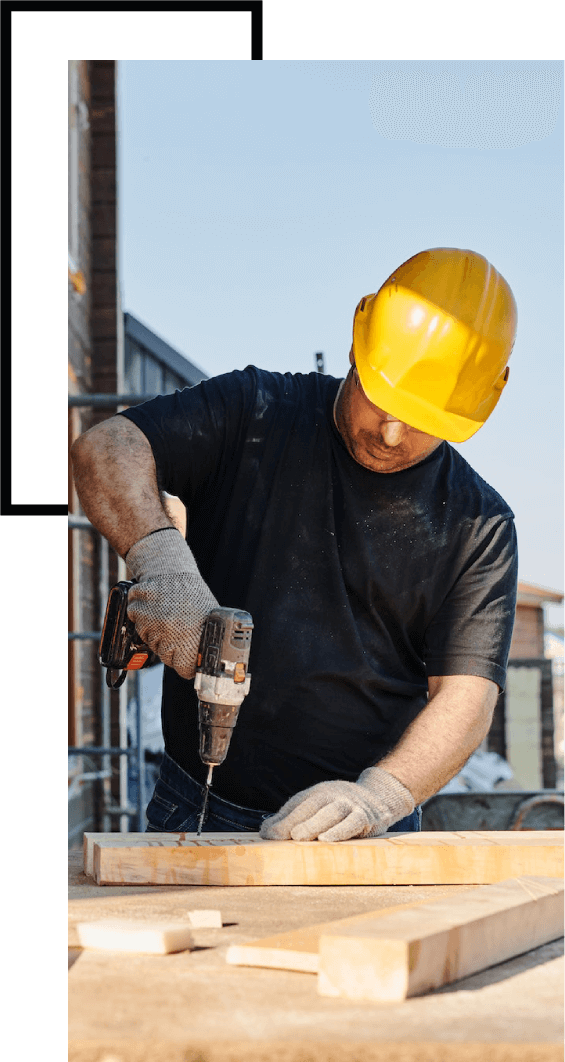 A man in hard hat and gloves using an electric drill.