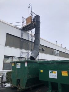 A large green dumpster in front of a building.