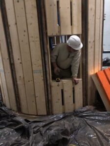 A man in white hard hat looking into a hole.