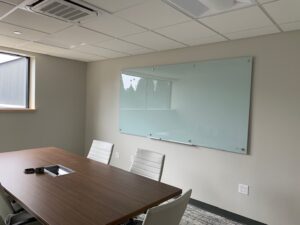 A conference room with a large glass board on the wall.