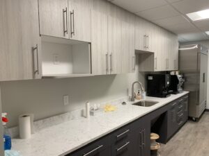 A kitchen with white cabinets and black drawers.