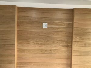 A wooden wall with some white trim and a light switch.