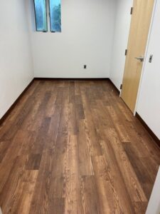 Photo of an empty room with brown vinyl flooring.