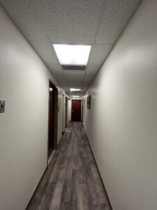 A long hallway with white walls and brown wooden doors.